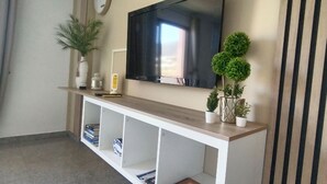 Una sala de estar con un televisor de pantalla plana montado en la pared, una consola de madera con plantas decorativas, y un panel de pared a rayas.