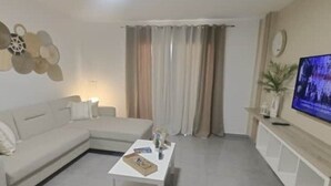 Una sala de estar moderna con un sofá modular, una mesa de centro y un televisor de pantalla plana.