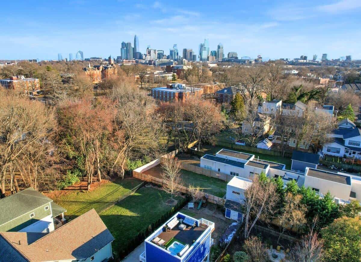 Un quartier résidentiel avec des maisons modernes, une grande pelouse verdoyante et, en arrière-plan, le panorama de la ville.