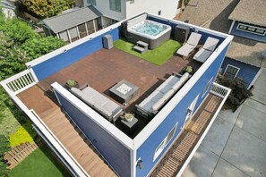 Terraza en la azotea con jacuzzi, zona de estar y un pequeño jardín.