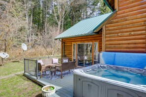Une cabane en bois dotée d’un bain à remous, d’une terrasse et d’un espace salon extérieur.