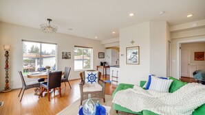 A spacious living room with a green sofa, dining area with a round table, and a kitchen in the background. - Beautiful Birch Bay Retreat w/ Deck & Fire Pit! (Blaine)
