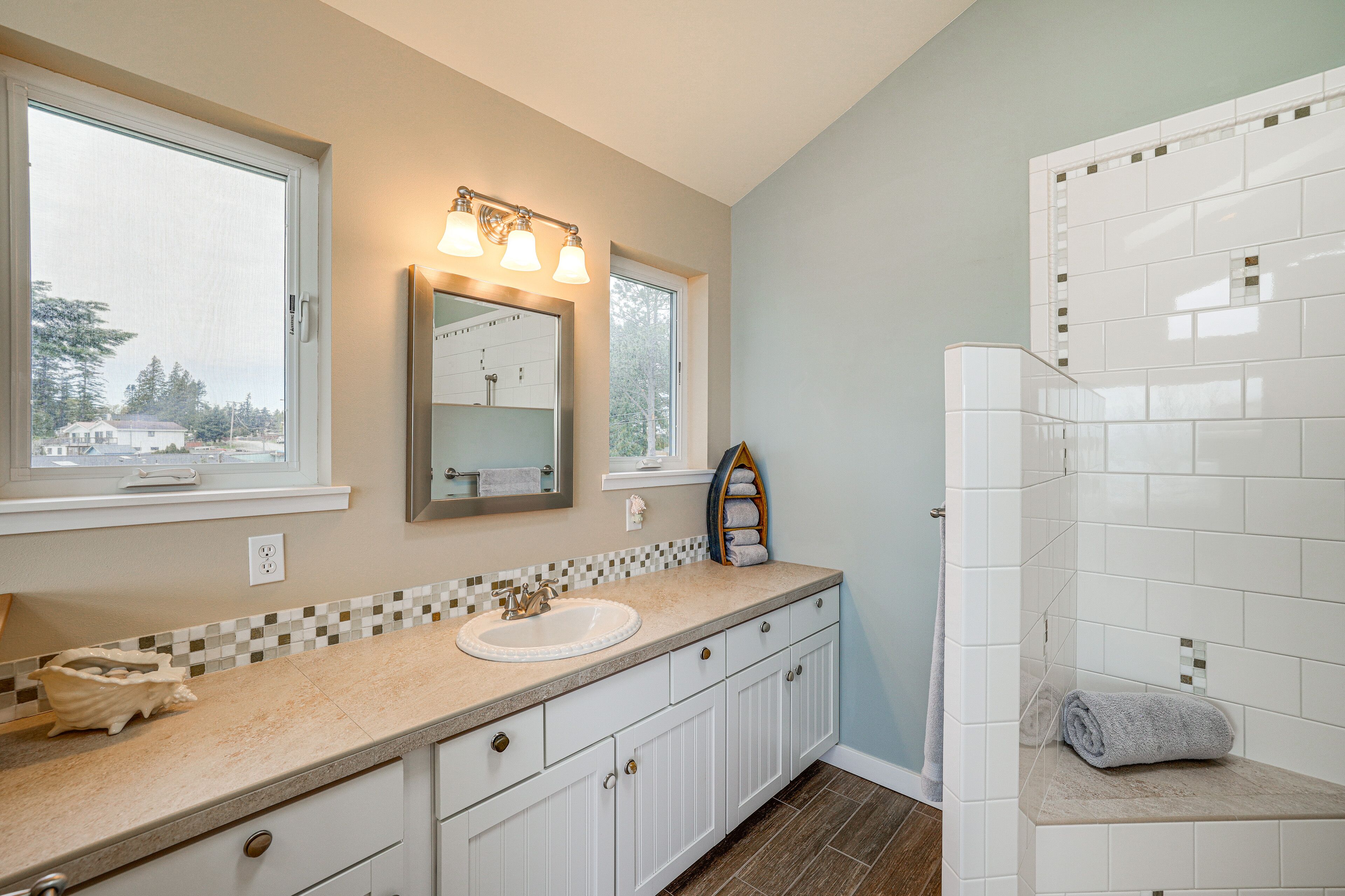 A bathroom with a sink, mirror, and shower.