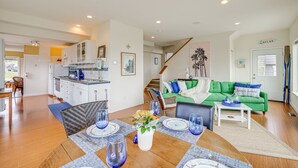 A spacious living area with a dining table set for four, a green sofa, and a kitchen in the background. - Beautiful Birch Bay Retreat w/ Deck & Fire Pit! (Blaine)