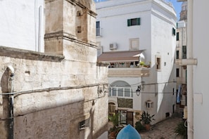 A narrow street with buildings, a stone wall, and a blue dome structure. - WePuglia - Porta Blu (Monopoli)