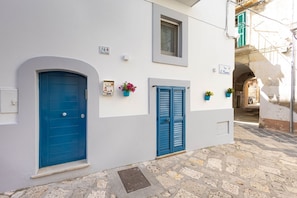 A narrow street with white buildings, blue doors, and a stone pavement. - WePuglia - Porta Blu (Monopoli)