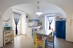 A compact kitchen with a dining area, a microwave, a refrigerator, and a table with chairs.