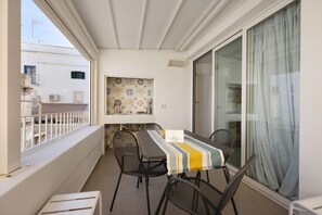 Un balcón con mesa y sillas, vistas a edificios y una pared con diseño.