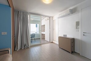 A room with a sliding glass door leading to a balcony, a small cabinet, and a bed.