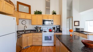 A modern kitchen with wooden cabinets, a stainless steel refrigerator, a microwave, and a stove. - Cozy Hailey Haven: Sun, Ski, Work, & Play at Your Doorstep (Hailey)