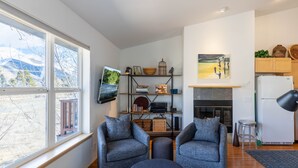 A modern living room with two grey sofas, a coffee table, a TV, and a bookshelf with various items. - Cozy Hailey Haven: Sun, Ski, Work, & Play at Your Doorstep (Hailey)