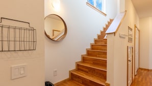 A staircase with wooden steps and a handrail, a round mirror on the wall, a light fixture, and a small window at the top. - Cozy Hailey Haven: Sun, Ski, Work, & Play at Your Doorstep (Hailey)