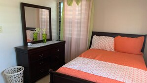 Un dormitorio con cama, cómoda, espejo y cortinas.
