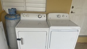 Lavadora y secadora compactas, blancas y de dos puertas, con mandos y un cilindro de gas cerca.