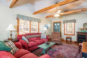 A cozy living room with a red sofa, a plaid armchair, a wooden ceiling, and a patterned rug. - CHARMING Saluda on My Mind – 2min Walk to Downtown (Saluda)