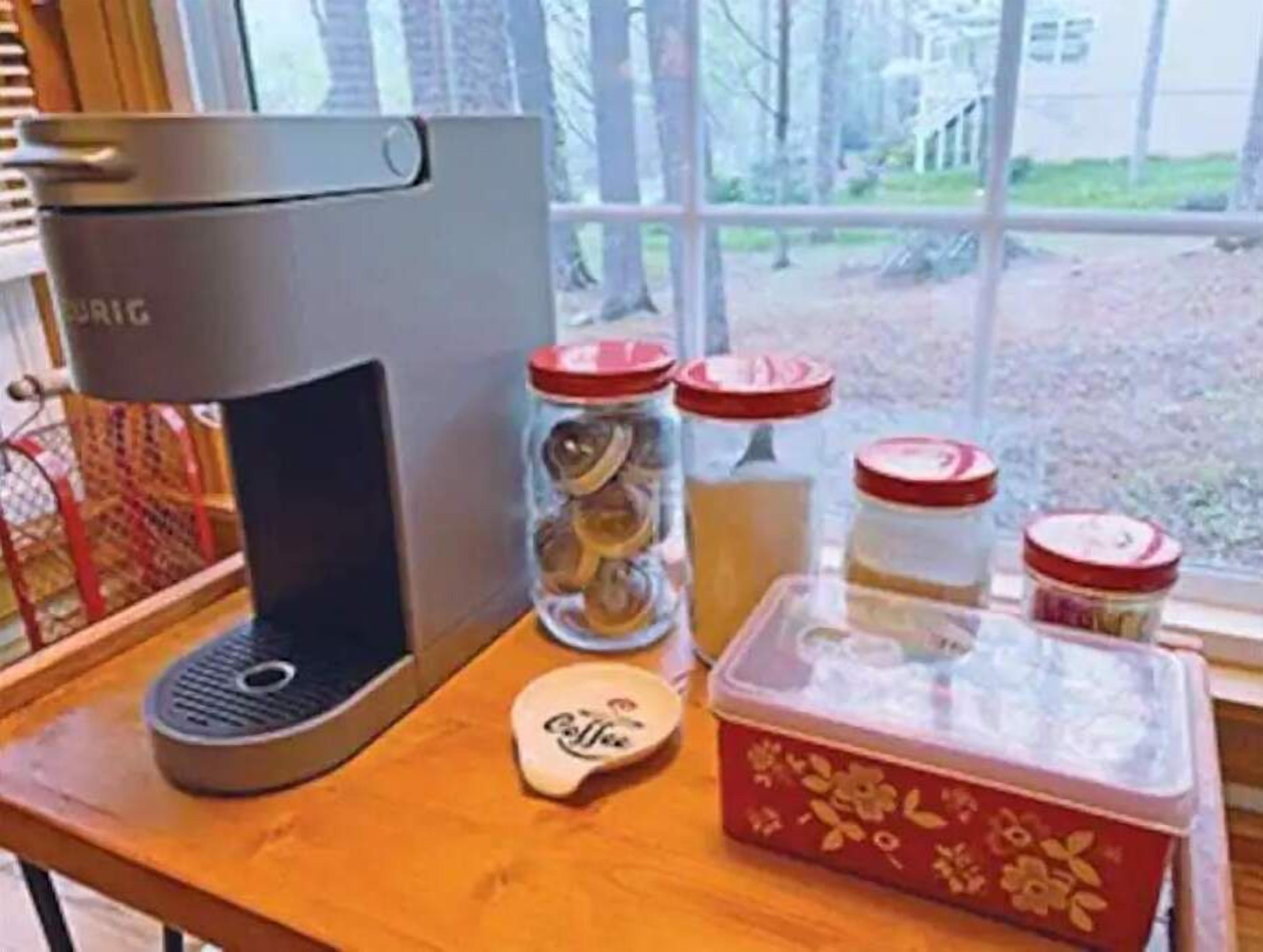 A kitchen counter with a coffee maker, jars of spices, and a coffee pod holder.