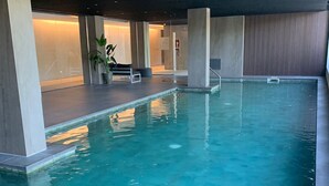En inomhuspool med kristallklart vatten, omgiven av modern arkitektur och minimalistiska designelement.