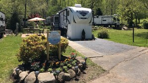 Valkoinen matkailuauto, jonka kyljessä on merkki ’SABRE’, on pysäköitynä leirintäalueelle, jossa on asfaltoitu ajotie ja opaste, jossa lukee ’Bob’s RV Park’.