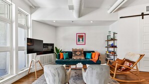 Uma sala de estar moderna com um sofá, duas poltronas, uma TV e uma estante.