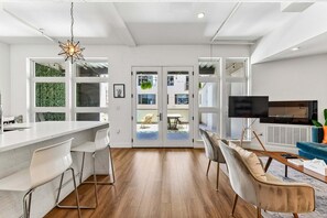 A modern kitchen with a white countertop, bar stools, and a hanging light fixture. - Bohemian Hideaway | RiNo Art Lofts (Denver)