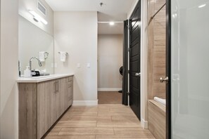 Un baño moderno con tocador de madera, un espejo y zona de ducha.
