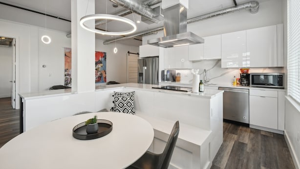 A modern kitchen with white cabinetry, stainless steel appliances, and a central island with seating. - Art District Dream | RiNo Art Lofts (Denver)