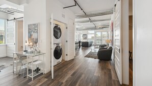A modern interior with a dining area, a laundry room, and a living space with a sofa and coffee table. - Art District Dream | RiNo Art Lofts (Denver)
