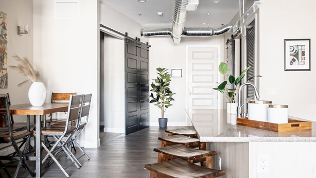 Une cuisine moderne avec un îlot central, des chaises en bois, une table à manger et une plante en pot.