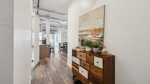 A hallway with a wooden floor, a wooden cabinet with drawers, and a painting on the wall. - Brushed & Bold | RiNo Art Lofts (Denver)