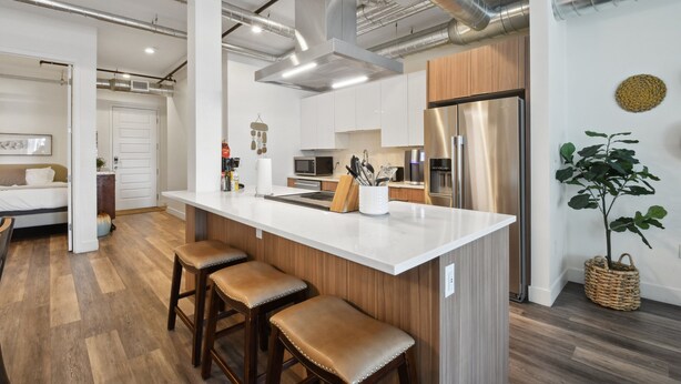 A modern kitchen with a large island, stainless steel appliances, and wooden accents. - Brushed & Bold | RiNo Art Lofts (Denver)