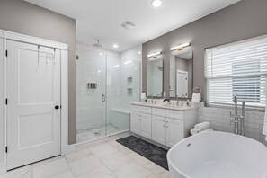 Une salle de bain moderne dotée d’une douche à l’italienne, d’une grande baignoire et d’un meuble-lavabo avec un miroir.