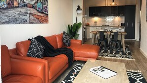 A modern living room with a leather sofa, a coffee table, and a painting on the wall. - Funky Fitzroy 2 bedroom Apartment in Old Chocolate Factory (Fitzroy)