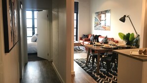 A modern living room with a dining area, a sofa, a coffee table, and a painting on the wall. - Funky Fitzroy 2 bedroom Apartment in Old Chocolate Factory (Fitzroy)