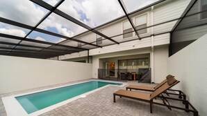 Un espace piscine sur le toit offrant une vue dégagée sur le ciel, une piscine et deux chaises longues.