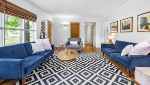 Ein Wohnzimmer mit zwei blauen Sofas, einem runden Couchtisch und einem gemusterten Teppich.
