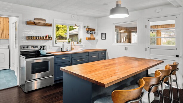 A modern kitchen with a large island, stainless steel appliances, and wooden bar stools.