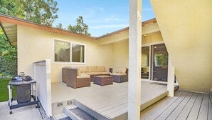 A covered outdoor patio with a sofa set, a grill, and a sliding glass door leading to an interior space. - Family Haven: Sports court/ Game Room/ King Beds (La Mesa)