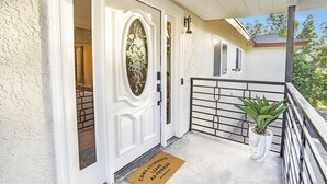 A white door with a decorative glass panel, a potted plant on the porch, and a doormat with text. - Family Haven: Sports court/ Game Room/ King Beds (La Mesa)