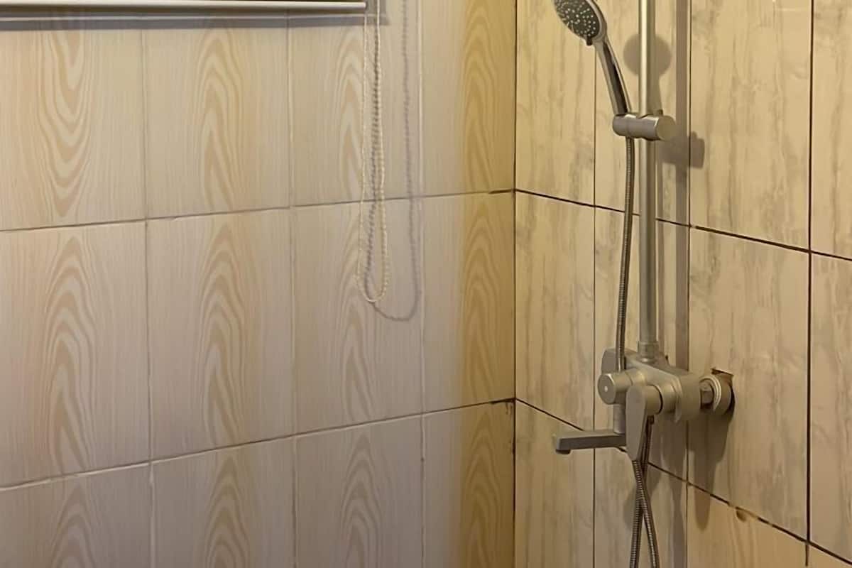 A shower with a handheld showerhead and a wall-mounted control panel.