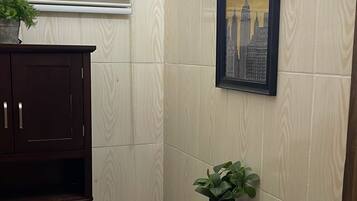 A bathroom with a toilet, a cabinet, a framed picture, and a plant.