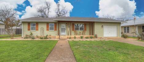 A single-story house with a front porch, a small front yard, and a clear sky.