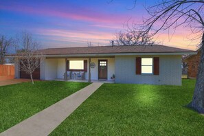 A single-story house with a front porch, a visible garage door, and a well-maintained lawn. - Crystal Cow Haus! (Fredericksburg)