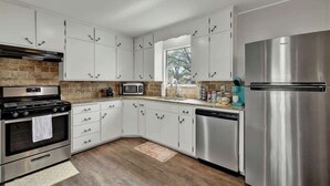 Una cocina moderna con armarios blancos, electrodomésticos de acero inoxidable y un respuesto de ladrillo.