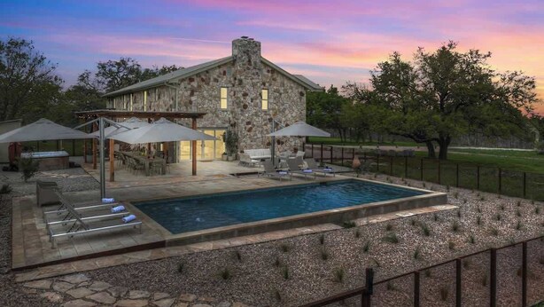 A stone house with a pool, outdoor furniture, and umbrellas. - Grasslands Pool Hot Tub Hill Country Views (Johnson City)