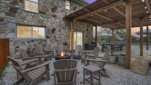 A stone building with a covered patio area featuring outdoor seating and a fire pit. - Grasslands Pool Hot Tub Hill Country Views (Johnson City)