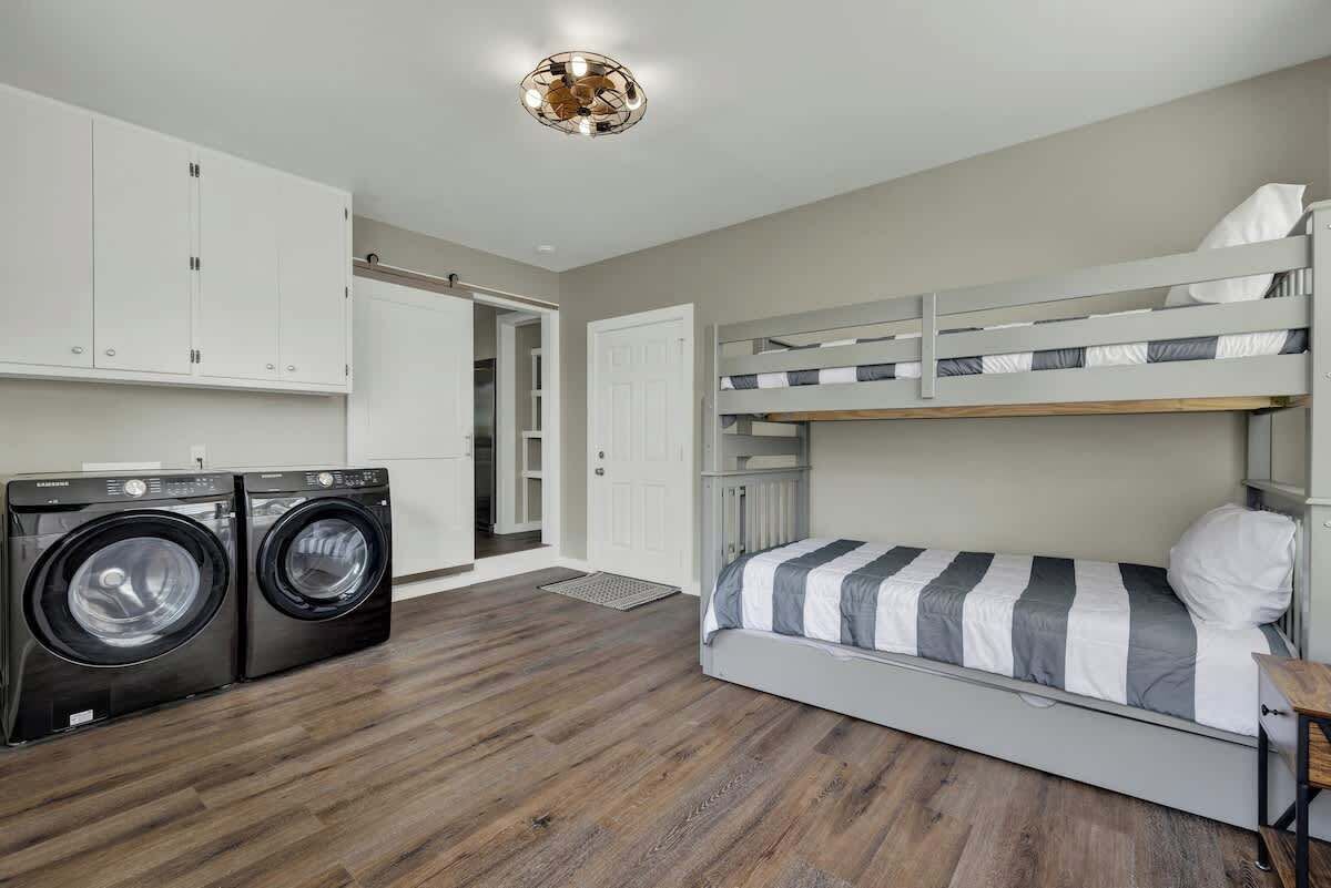 A compact room with a bunk bed, a washing machine, and a door leading to another room.
