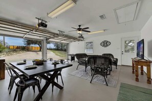 Habitación amplia con una mesa de comedor, sillas, un ventilador de techo y un gran ventanal con vistas al exterior.