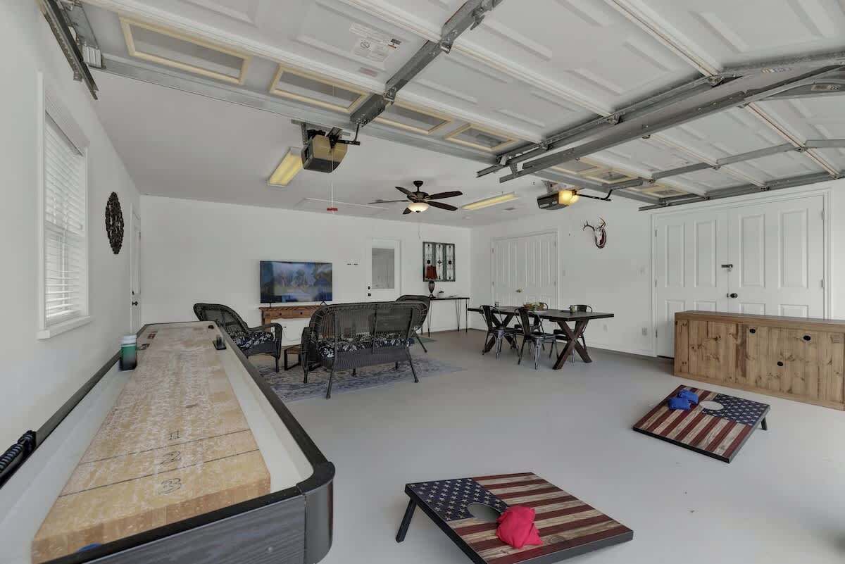 A spacious indoor area with a billiards table, seating, and a ceiling fan.