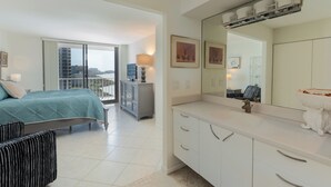 Una moderna camera d'albergo con un balcone, un letto, una toeletta con specchio e vista sulla città.
