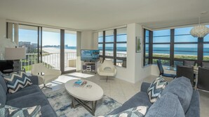 Un soggiorno moderno con una grande TV, posti a sedere confortevoli e un balcone vista spiaggia.